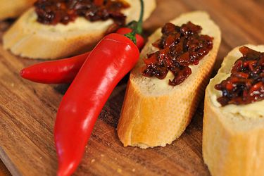 Hot chile chutney, served on slices of baguette. Two hot red chiles are nestled between the slices.