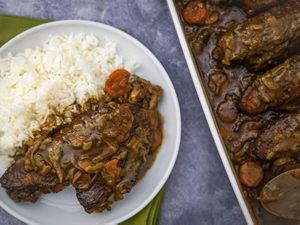 Overhead view of smothered turkey wings, served with rice.