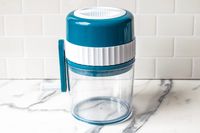 MANBA Ice Shaver and Snow Cone Machine with a blue top and a handle on a marble countertop, likely for food processing or grating