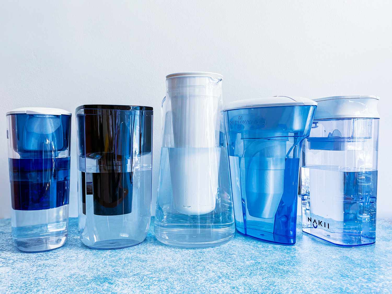 The lineup of water filter pitchers on a blue countertop.