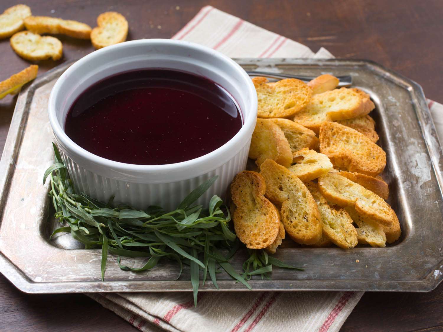 A ramekin of chicken liver pate next to pieces of toasted bread on a serving plate. 