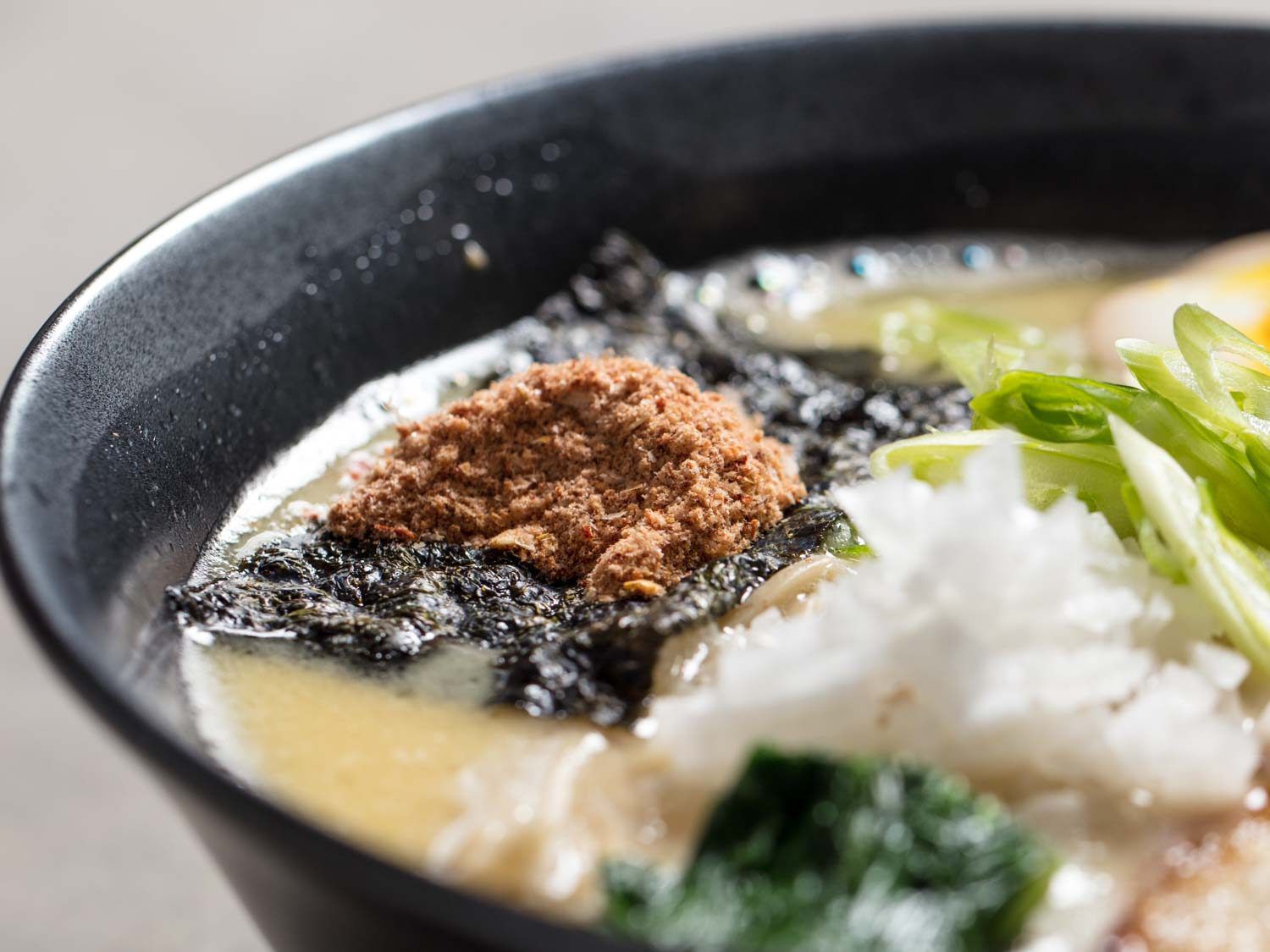 Close up of chili gyofun on top of a bowl of chicken paitan ramen