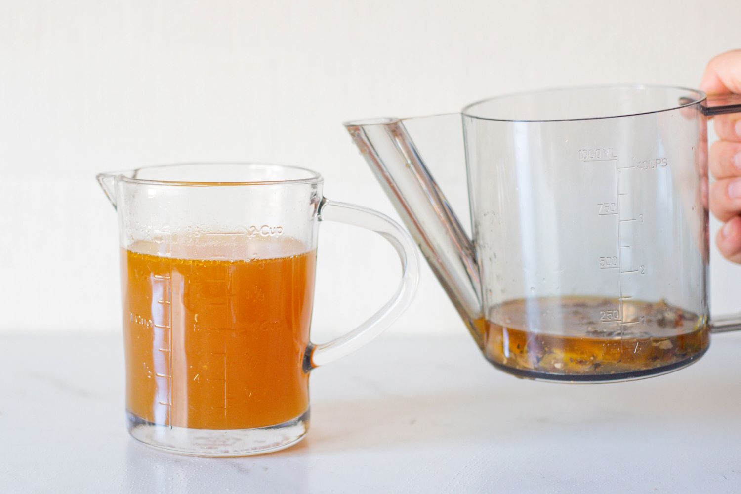 Two measuring cups one with liquid and the other being poured
