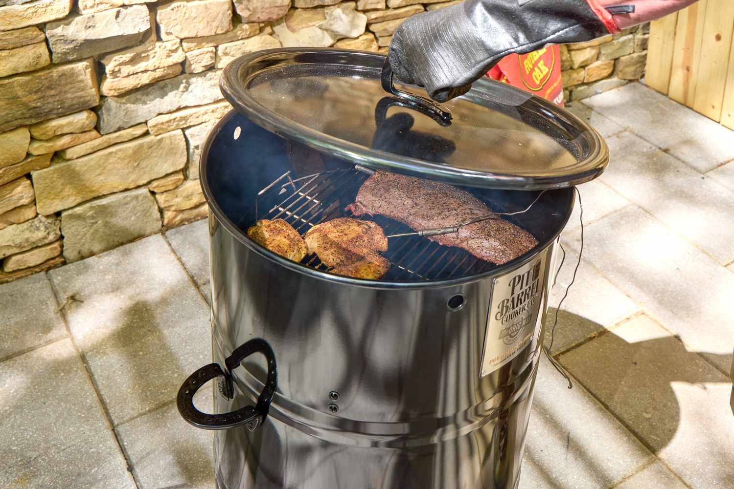 Barrel cooker in use outside, showing smoking food inside.