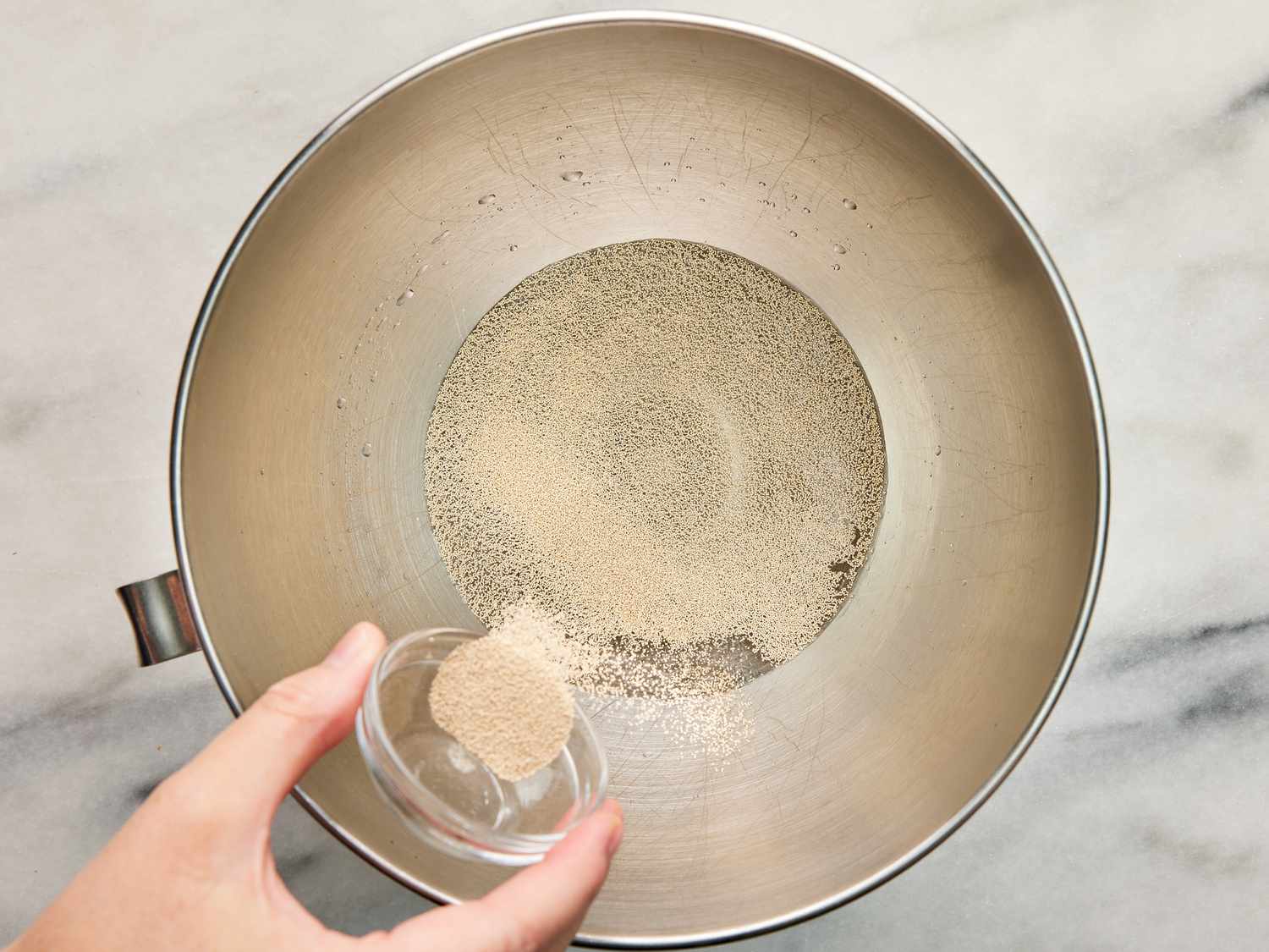 sugar being pouring into bowl of stand mixer filled with water