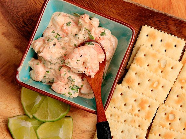 Colombian shrimp cocktail in a bowl with saltine crackers and lime wedges on the side.