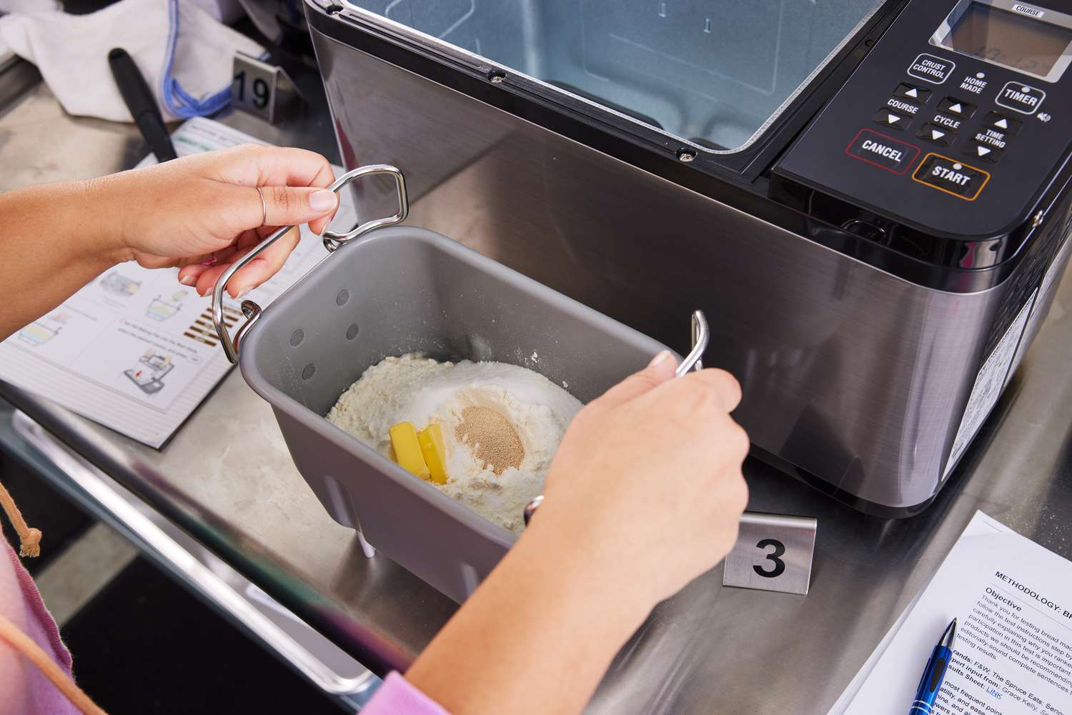 Hands holding basket of Zojirushi Home Bakery Virtuoso Plus Bread Maker with ingredients inside