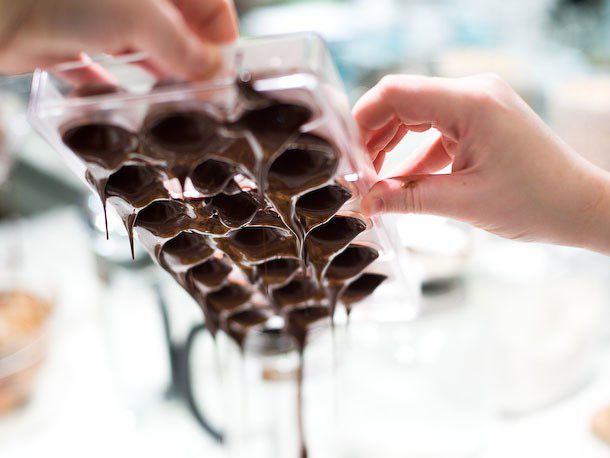 Pouring off excess melted chocolate from bonbon molds by inverting the mold.