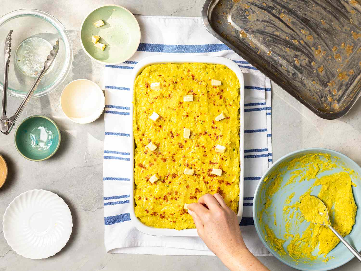 Butter pieces spread on top of assembled pastel de choclo