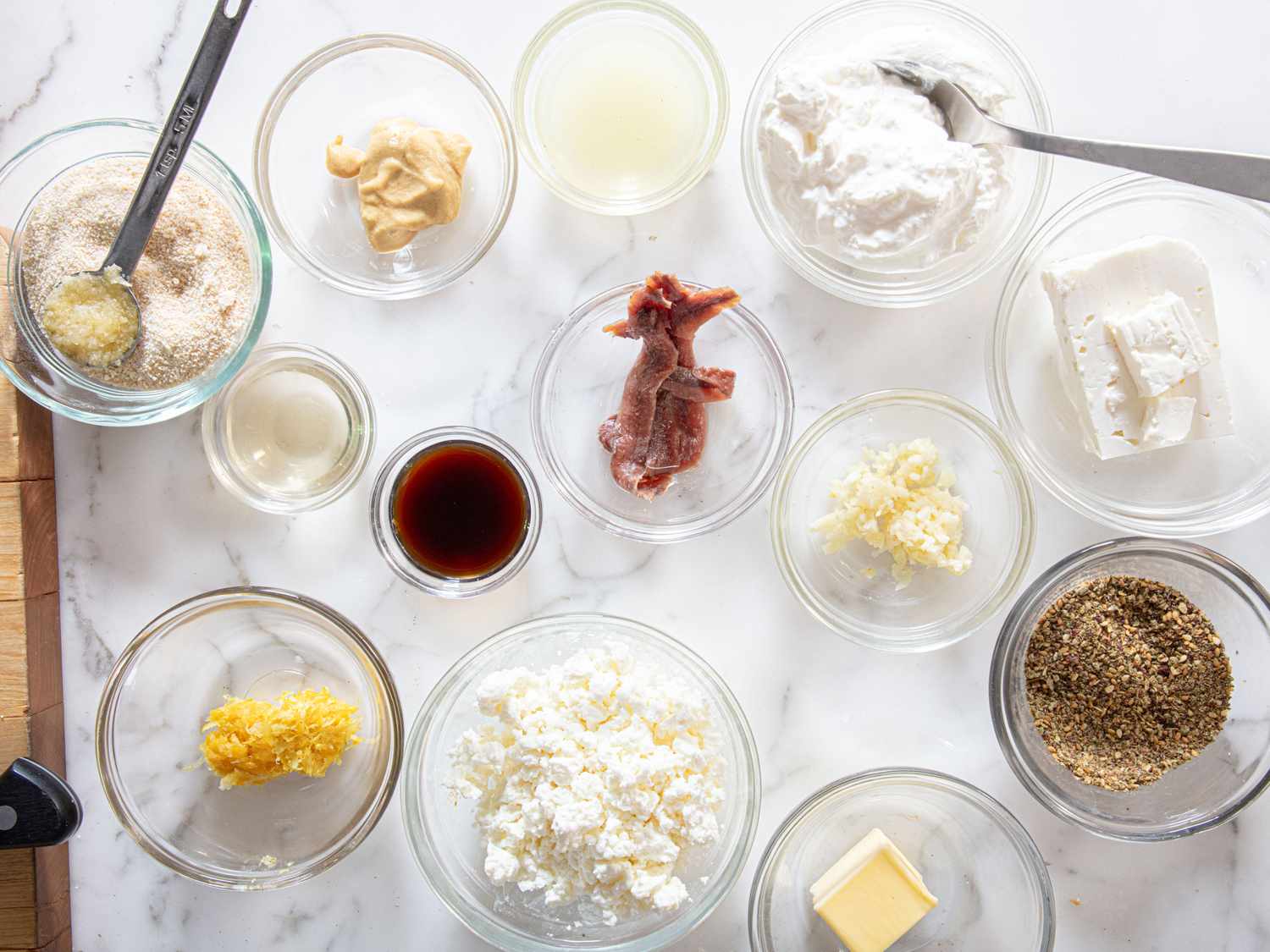 Ingredients in small bowls including cheese spices and a dressing component for preparing a salad
