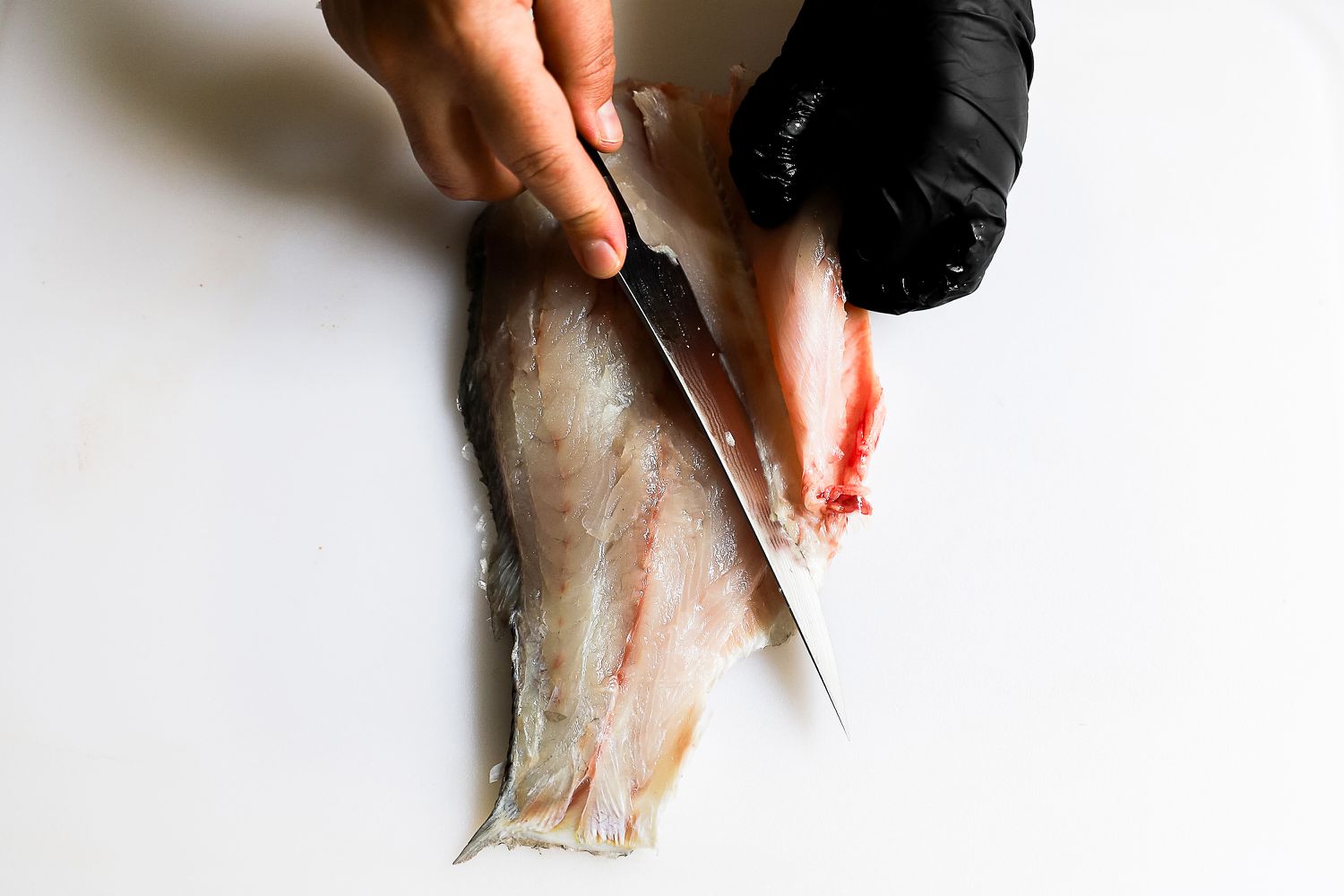 A person using the Shun Classic 6" Boning & Fillet Knife to slice a fish