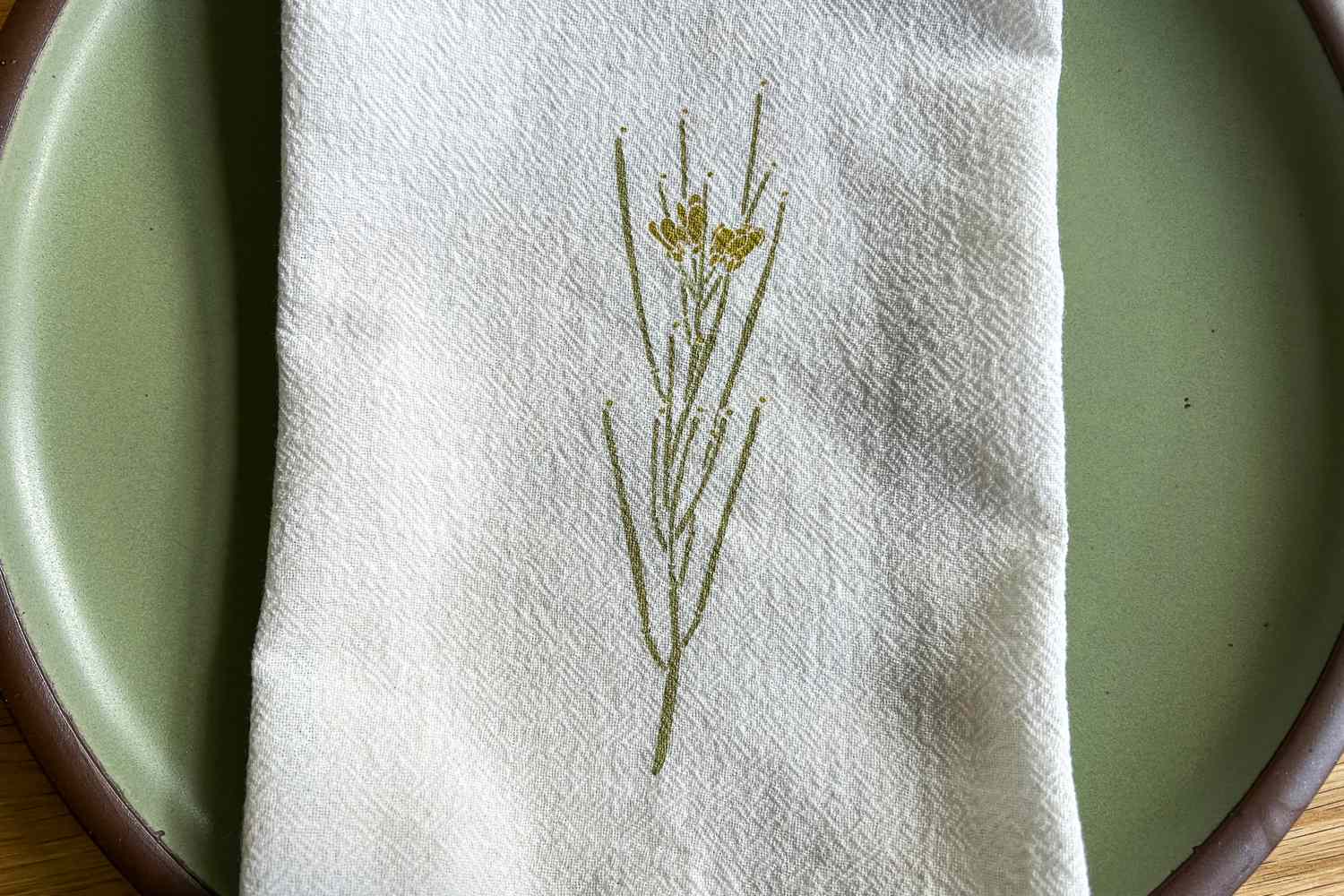 A cloth napkin with a floral design folded on a plate