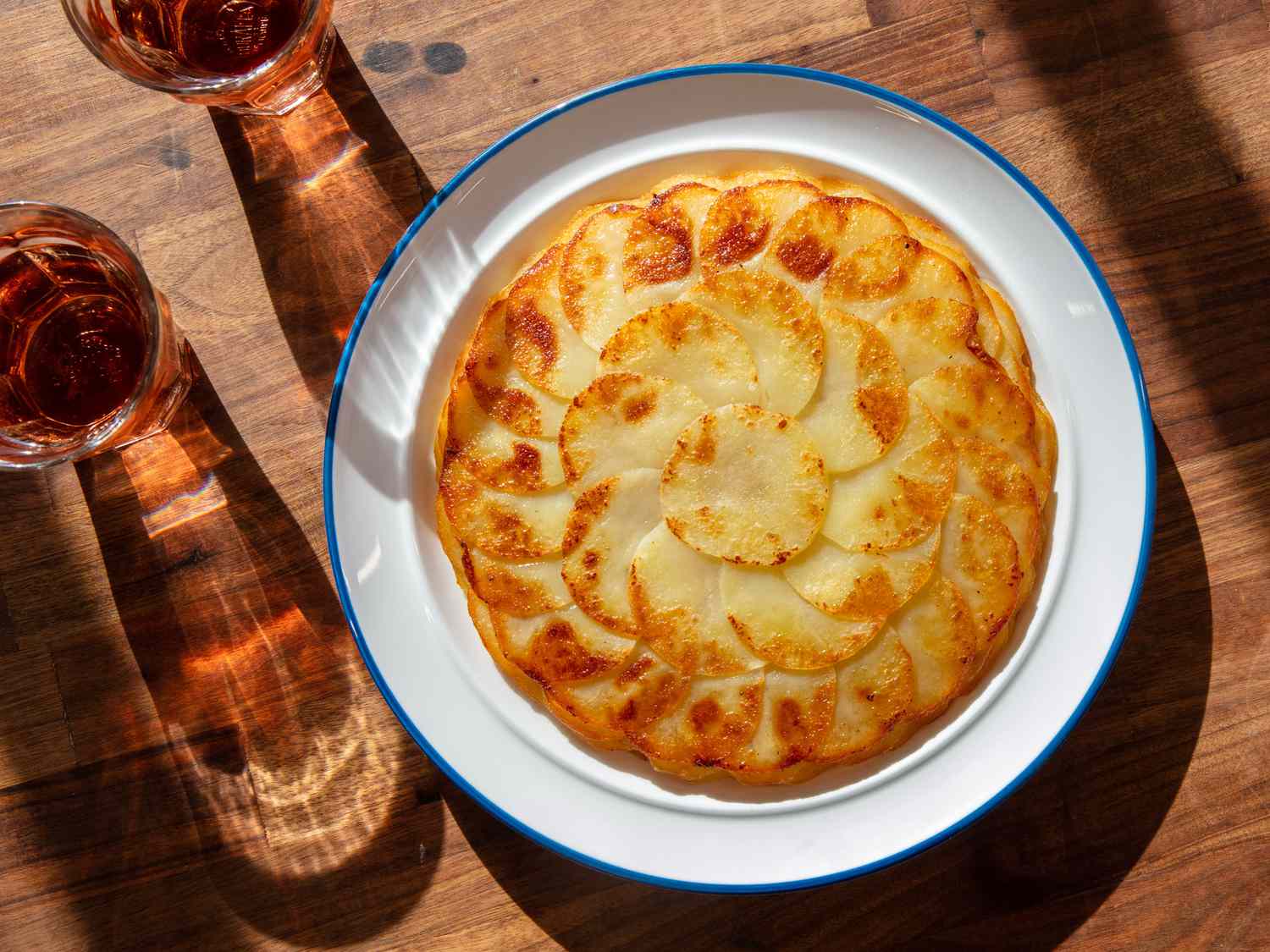 A pommes anna, golden on top, on a serving plate on the table.