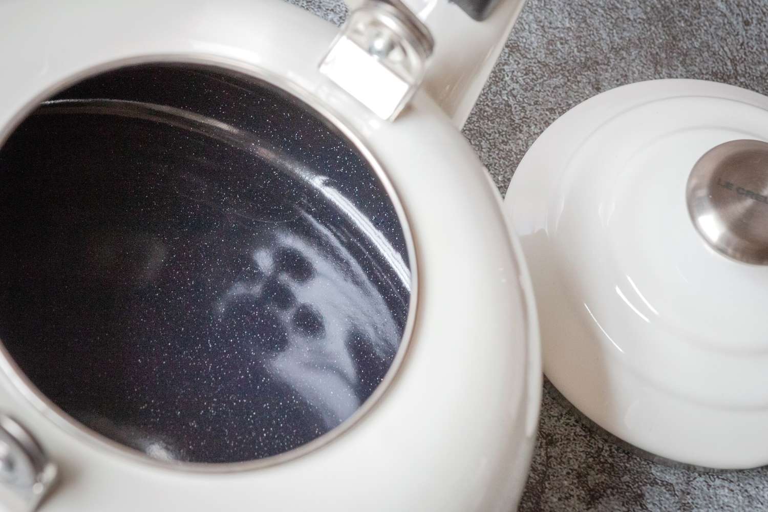 An open enamelkitchen kettle with a removed lid showing its interior