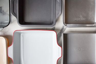 Numerous baking pans on a marble countertop.