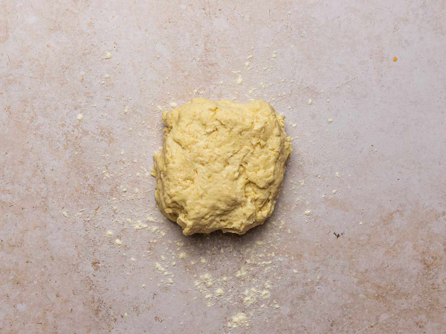 The ball of dough on a stone surface, after resting for fifteen minutes.