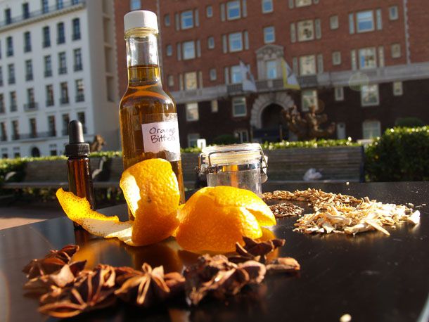 A bottle of homemade orange bitters standing behind some orange peel and star anise. 