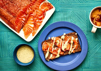 Overhead view of gravlax on pumpernickel bread with a coffee cup and sauce