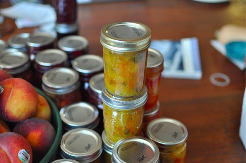 A table with many jars of homemade preserved goods stacked on each other. 
