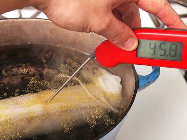 Taking temperature of foie gras torchon poaching in a Dutch oven. 