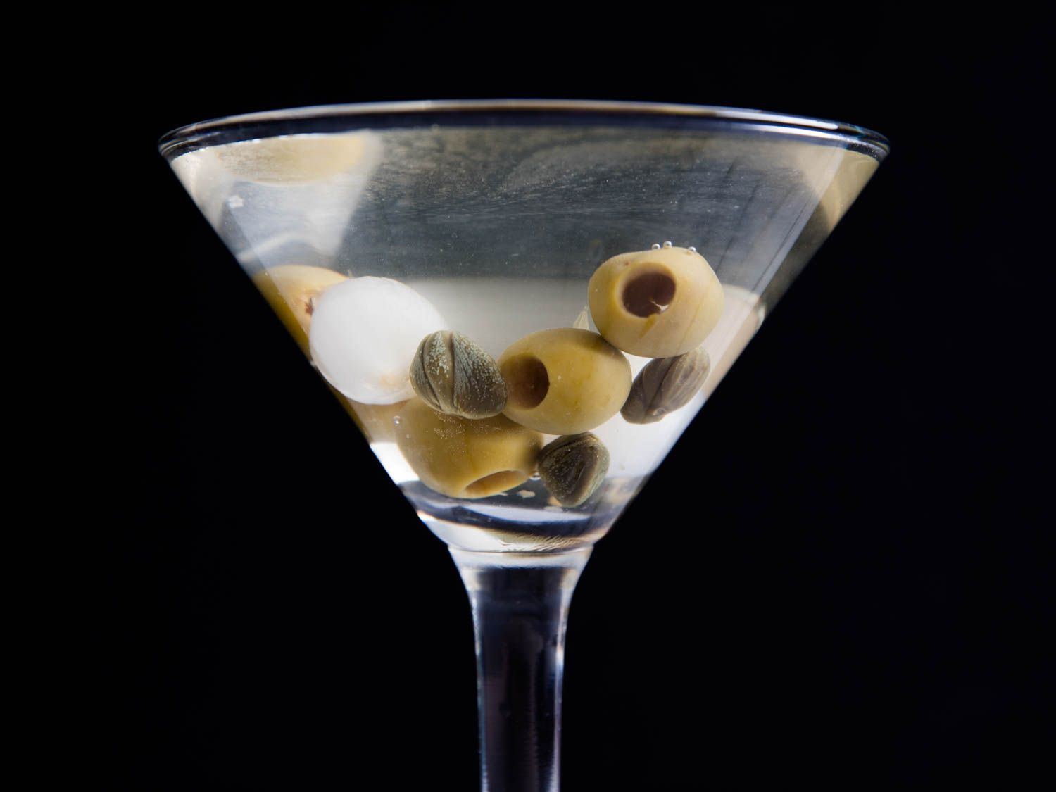 A dirty martini with olives, cocktail onions, and capers.