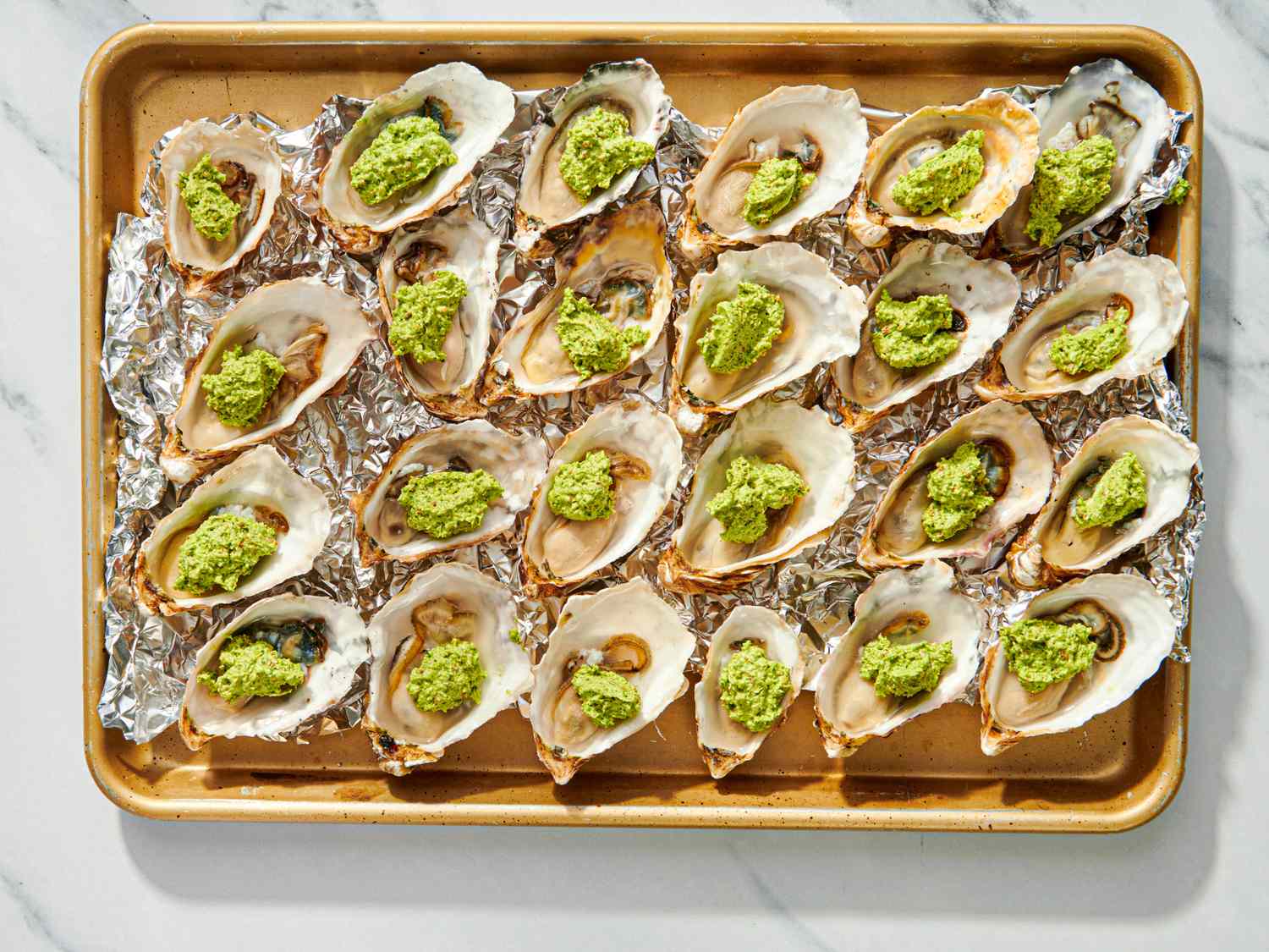Roasted oysters with green herb topping on a baking tray