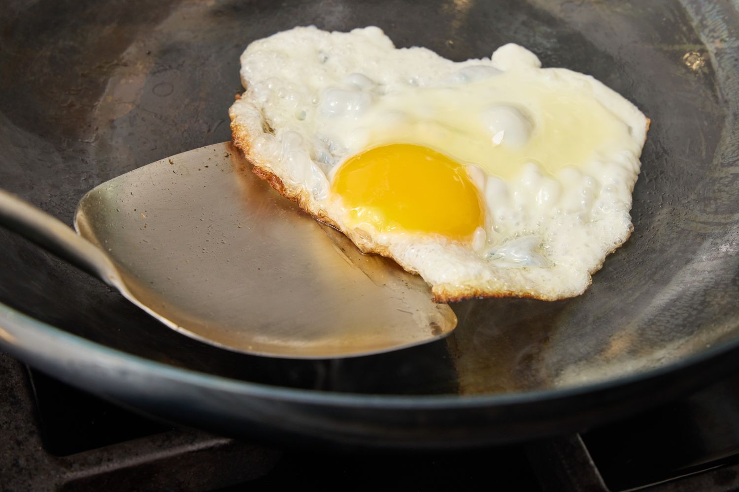 An egg frying in the Yosukata 13.5 Inch Pre-Seasoned Blue Carbon Steel Flat Bottomed Wok