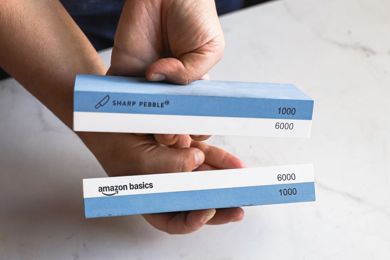 A person comparing two whetstones that look similar