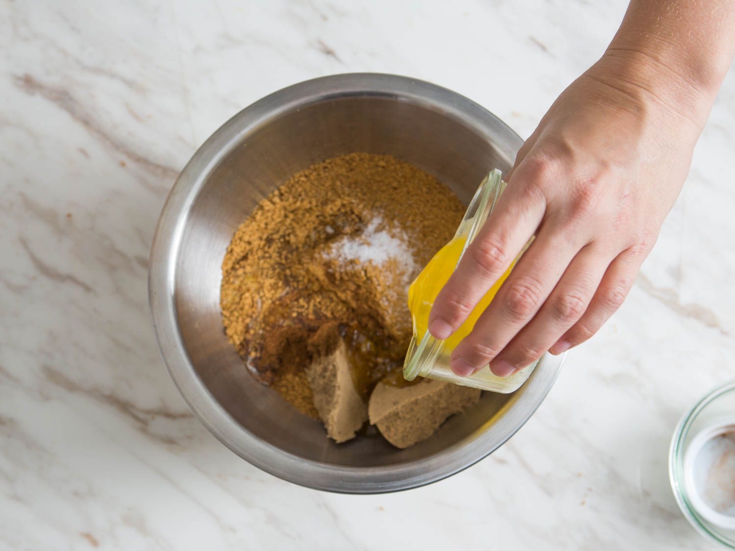 Pouring melted butter into a bowl of cookie crumbs and sugar to make a crust for pumpkin cheesecake.
