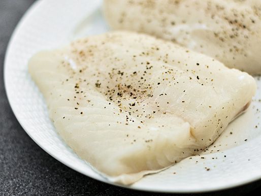 Seasoned uncooked fish fillets on a plate.