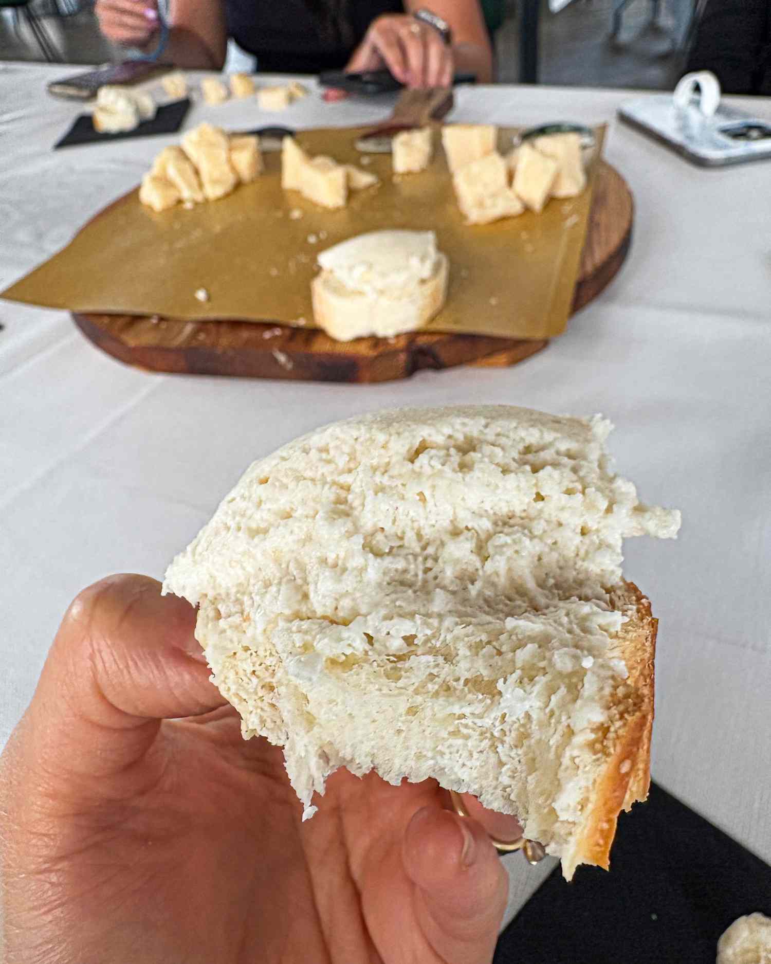 White bread being held with soft cheeses arranged on a board in the background