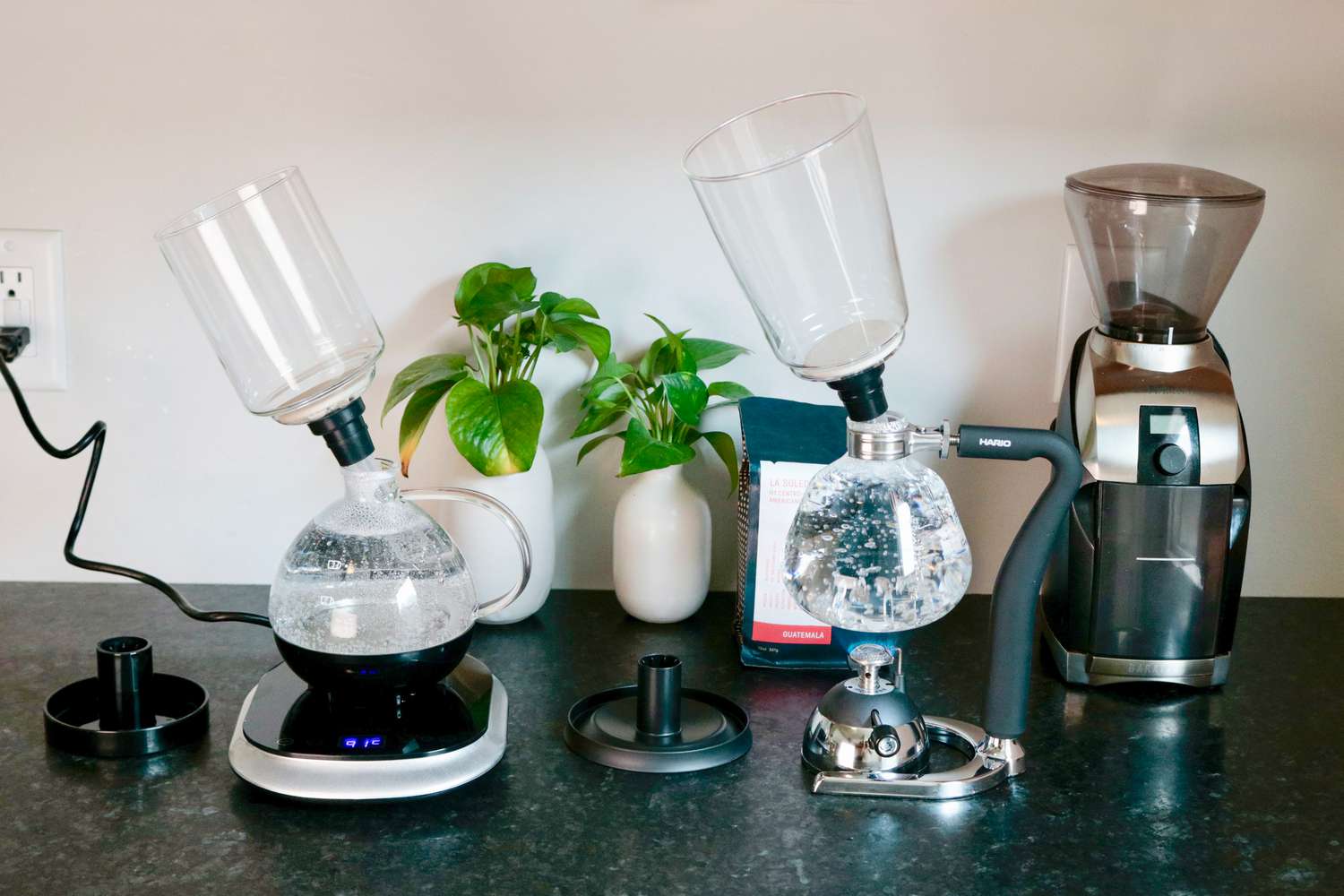 two siphon brewers on a grey countertopâone with boiling water and one with brewed coffee in the bottom