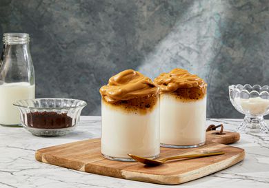 Two cups of Dalogna Coffee with ingredients surrounding it 