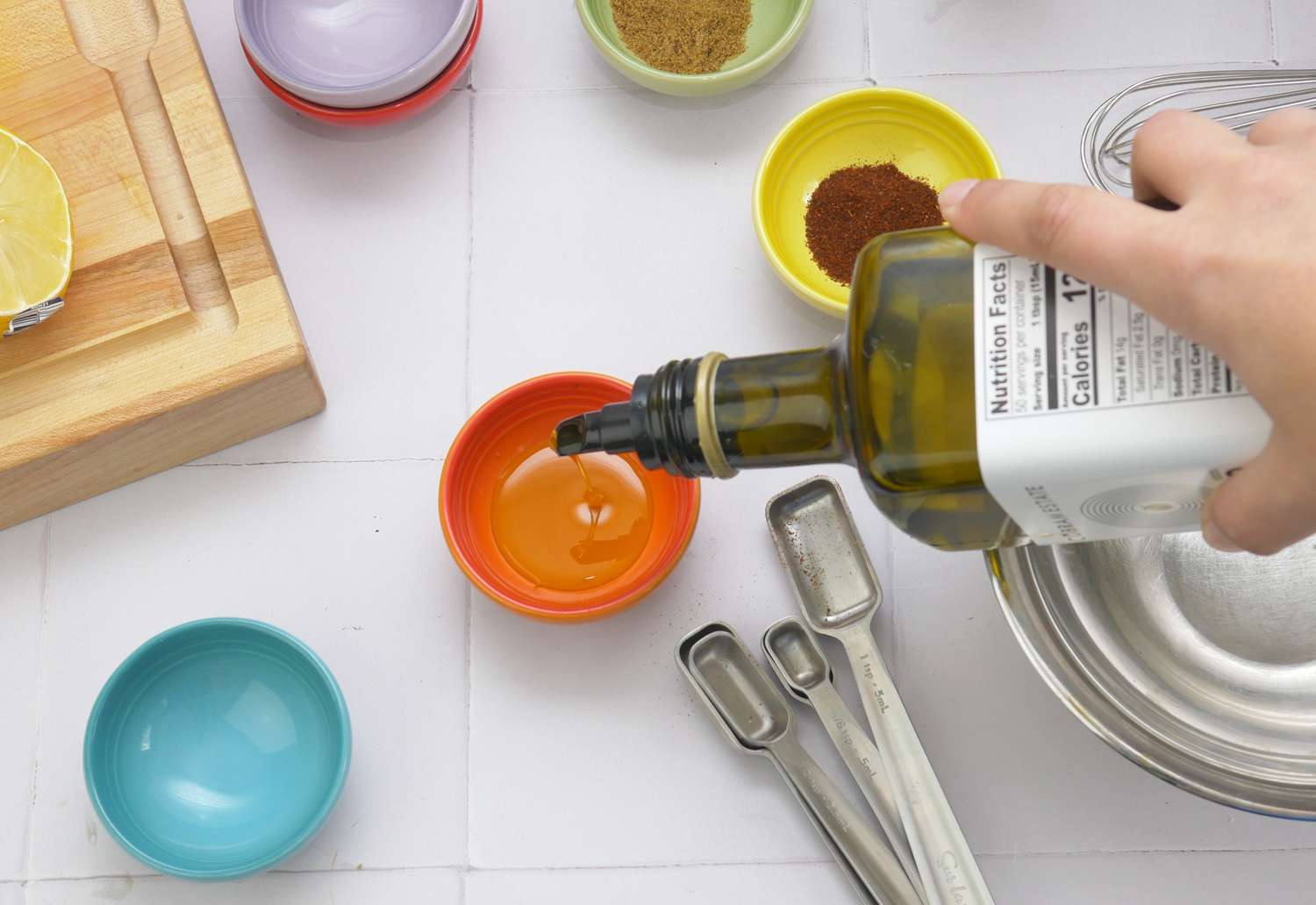 a person pouring olive oil into an orange pinch bowl
