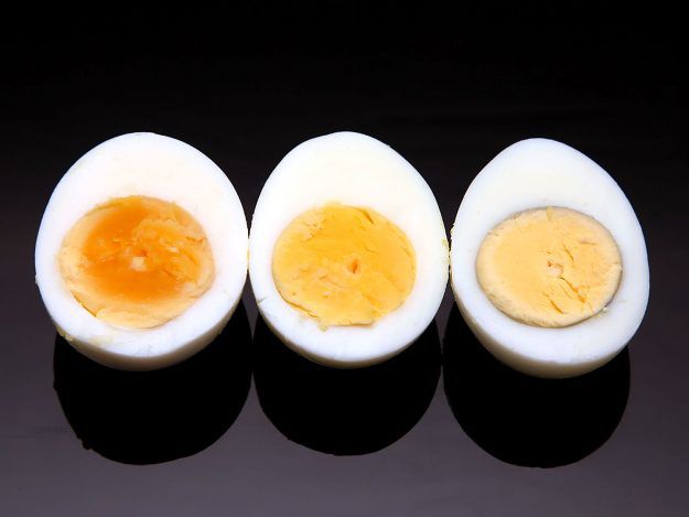Comparison of eggs pressure cooked for 5, 6, and 7 minutes. The yolk turns from bright orange to orange and yellow with a grey ring around it respectively.