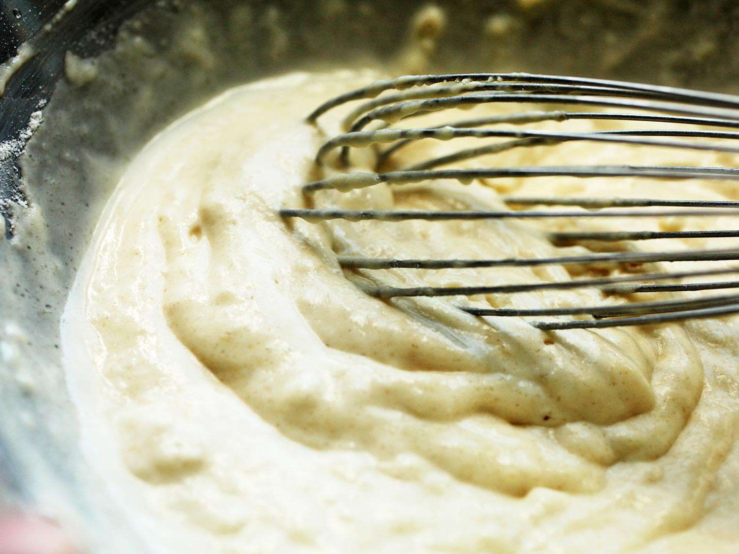 Closeup of whisk in bowl of thick pancake batter