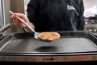 A person using the Tovolo Silicone Slotted Turner to flip a pancake