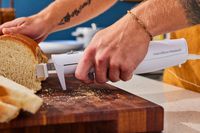 a person holding the hamilton beach electric knife and cutting bread