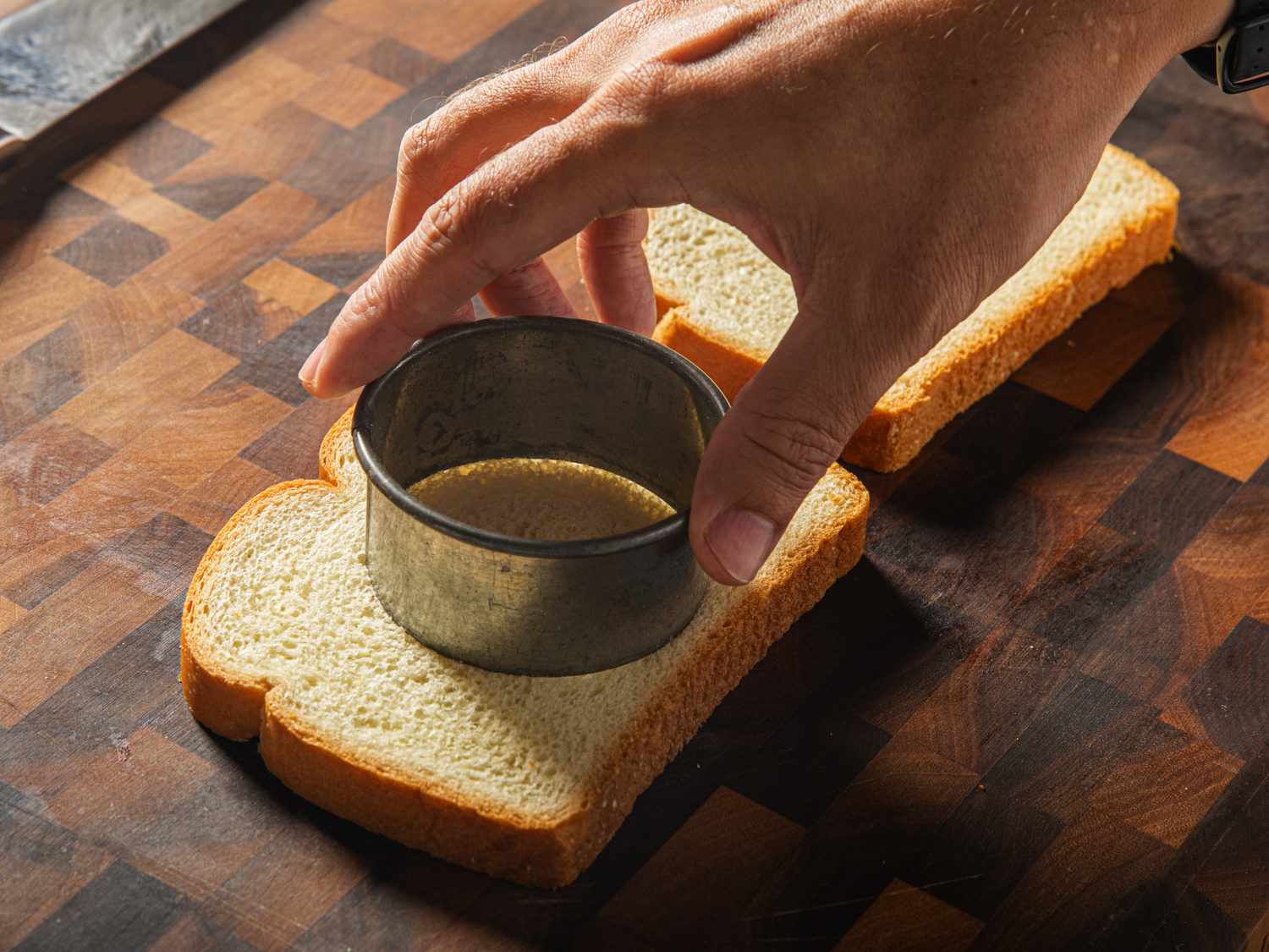 A circle being cut out of the middle of a piece of white bread with a pastry tin