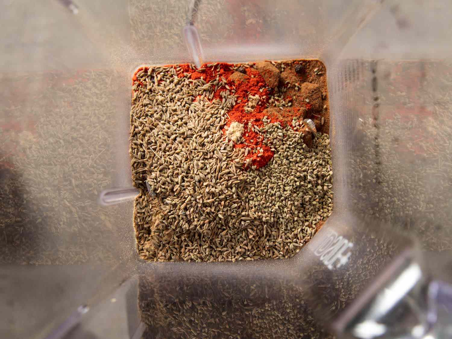 The toasted spices inside of the bowl of a high speed blender, but not yet blended.