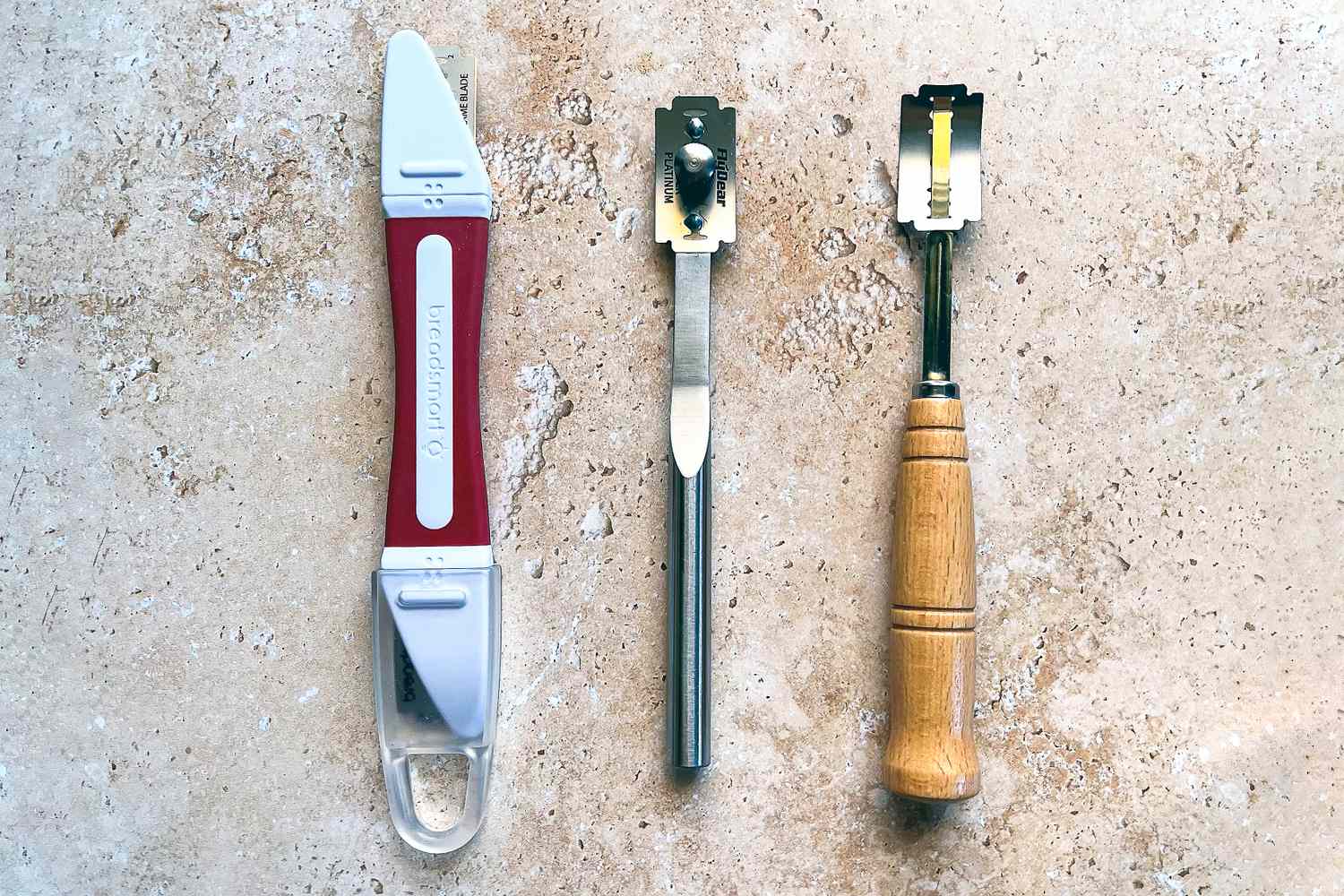 Three bread lames on a stone countertop