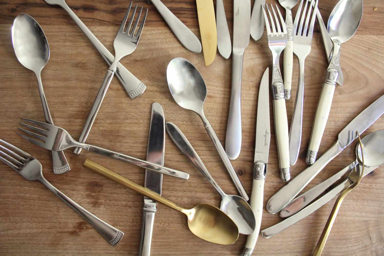 An assortment of silverware on a wooden surface