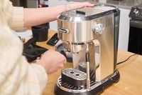 A person makes an espresso using the De'Longhi EC900M Dedica Maestro Espresso Machine
