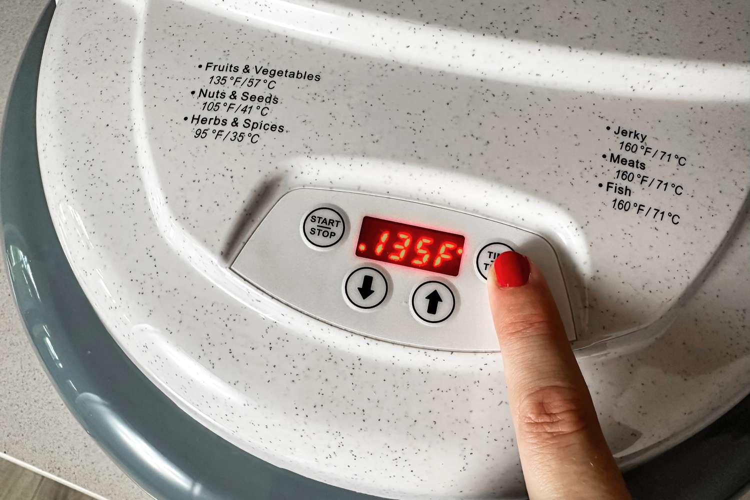 A person setting the temperature on the Nesco Gardenmaster food dehydrator