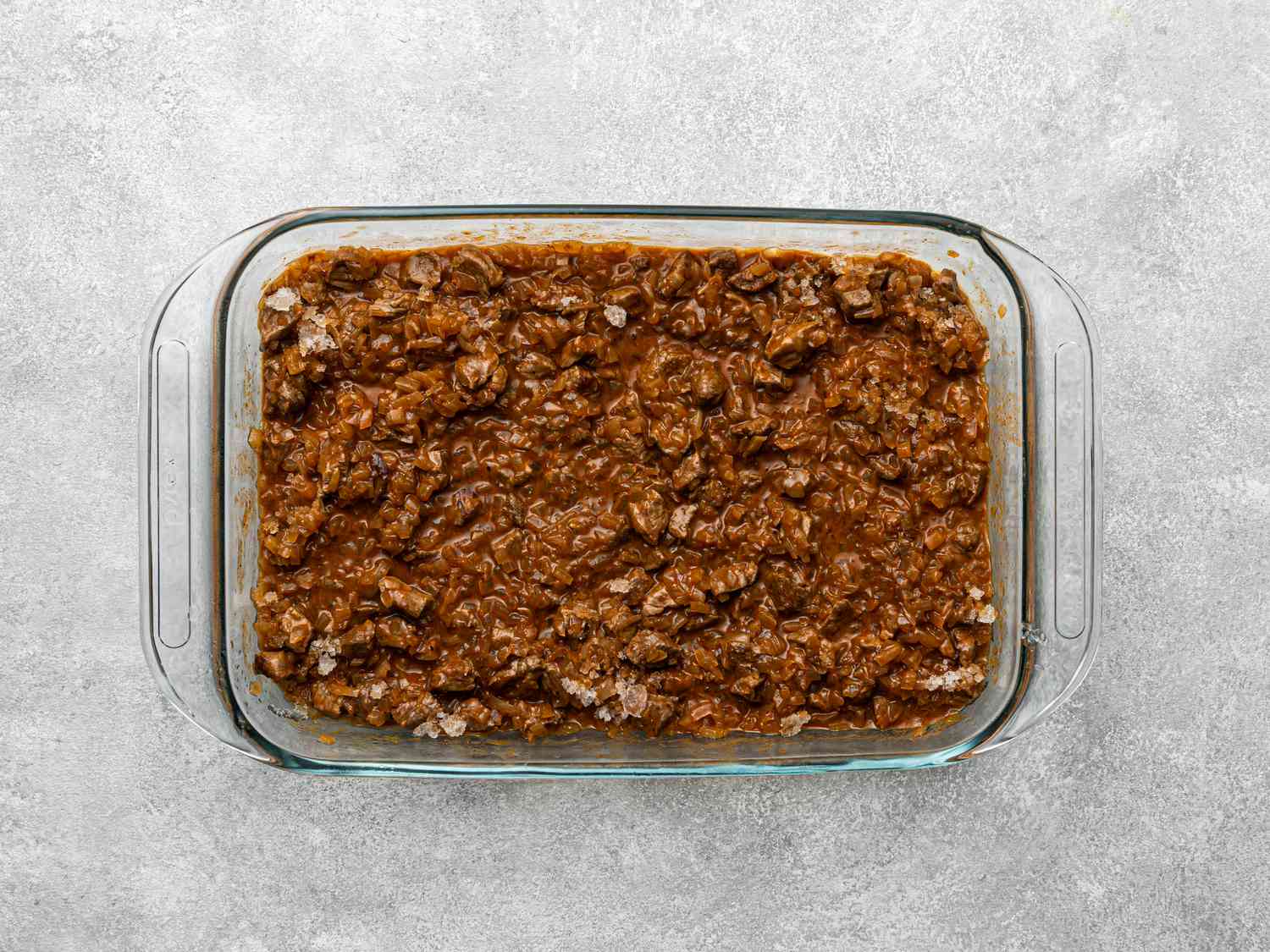 Ground beef filling in a glass baking dish, part of a preparation for Chilean beef empanadas.