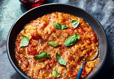Bowl of Pappa Al Pomodoro in a black bowl on dark blue surface, with dark dyed napkin and a glass of red wine 
