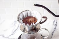 Pouring hot water over coffee grounds in a drip coffee maker pot