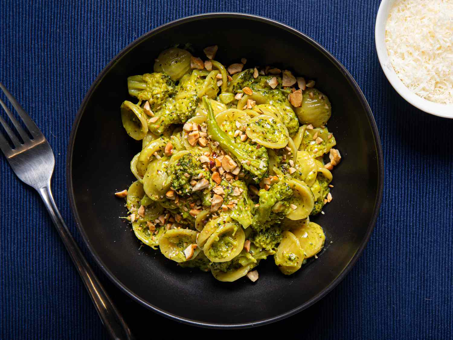 Orecchiette with broccoli and toasted hazelnuts in a black bowl.