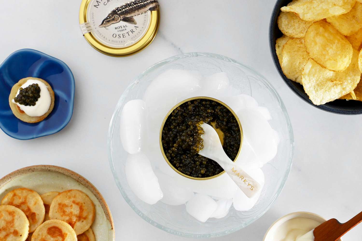 Marky's osetra caviar surrounded by potato chips, blinis, and crème fraîche.