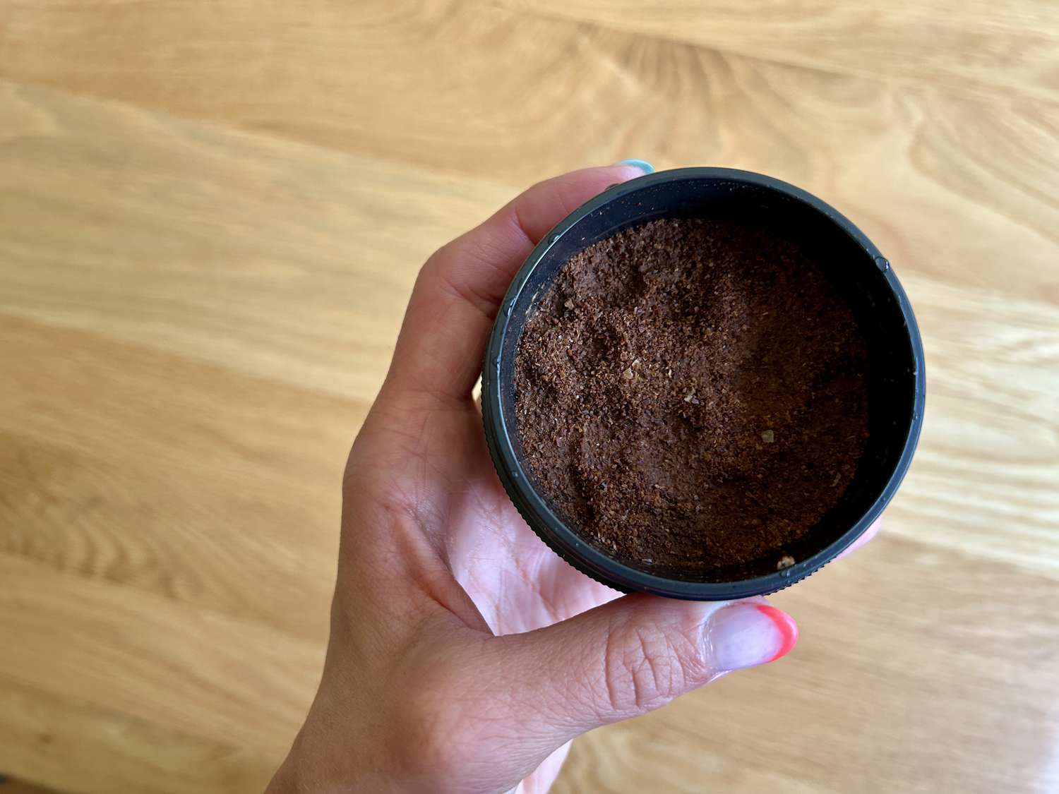 A hand holding a the coffee bin of the OXO Rapid Brewer full of spent coffee grounds.